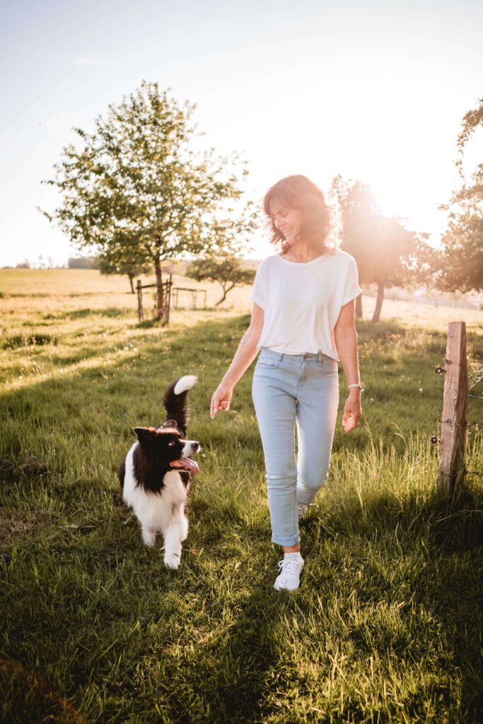 Anette Happ, freie Traurednerin, spaziert mit ihrem Hund über eine Sommerwiese